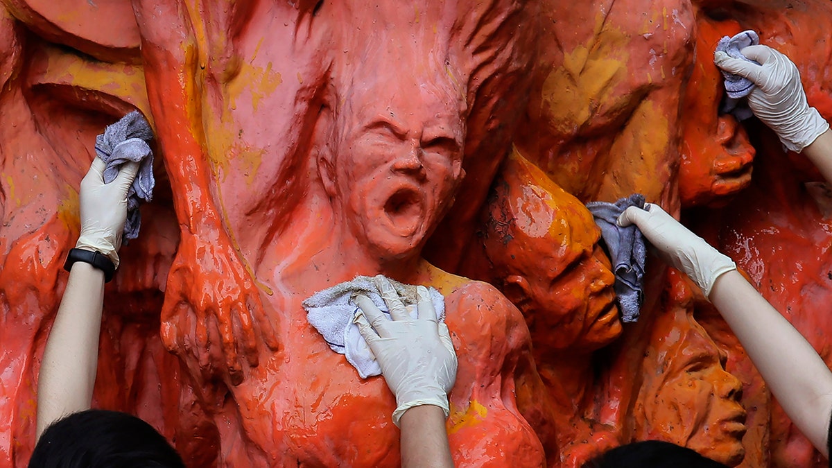 University students clean the "Pillar of Shame" statue, a memorial for those killed in the 1989 Tiananmen crackdown, at the University of Hong Kong Tuesday, June 4, 2019. 
