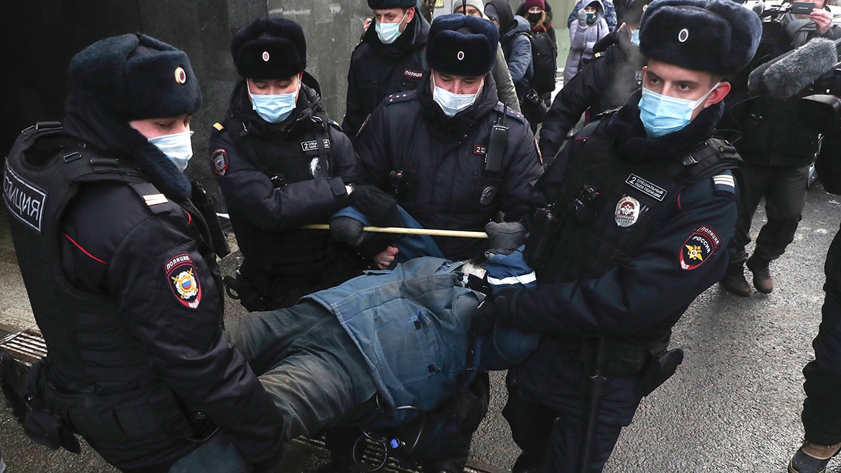 Police officers detain a demonstrator as people gather in front of the Supreme Court of the Russian Federation, in Moscow, Russia, Tuesday, Dec. 28, 2021.