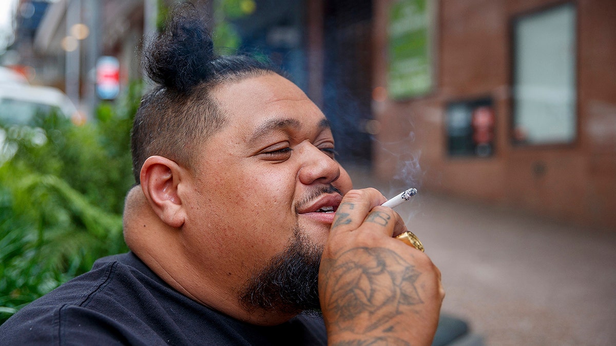 A man smokes on a street in Auckland, New Zealand, Thursday, Dec. 9, 2021.