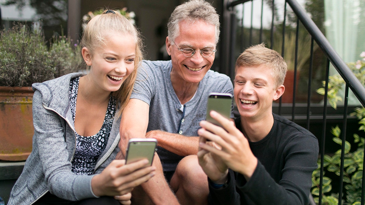 Duelmen, Germany - August 10: Two teenagers and their father are busy with their smartphones. Staged picture on August 10, 2017 in Duelmen, Germany. (Photo by Ute Grabowsky/Photothek via Getty Images)