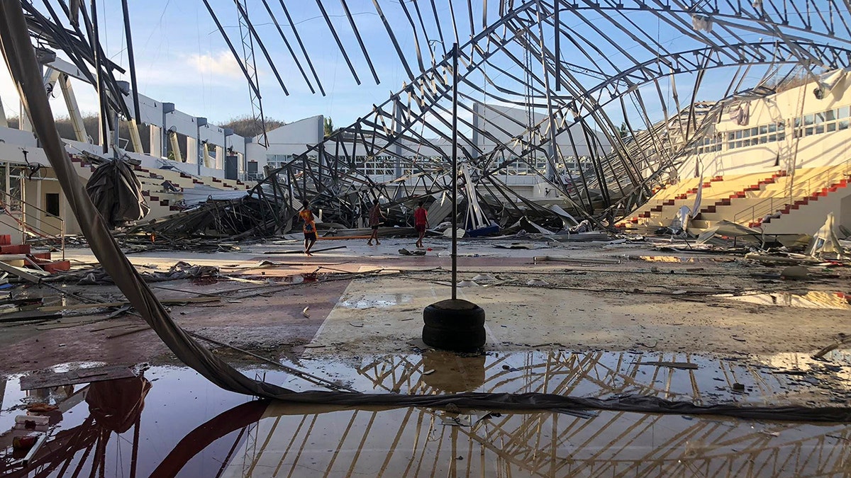 Residents walk inside a damaged sports complex building on Monday Dec. 20, 2021, that was used as an evacuation center when its roof collapsed due to Typhoon Rai at Siargao island in Surigao del Norte province, southern Philippines. 