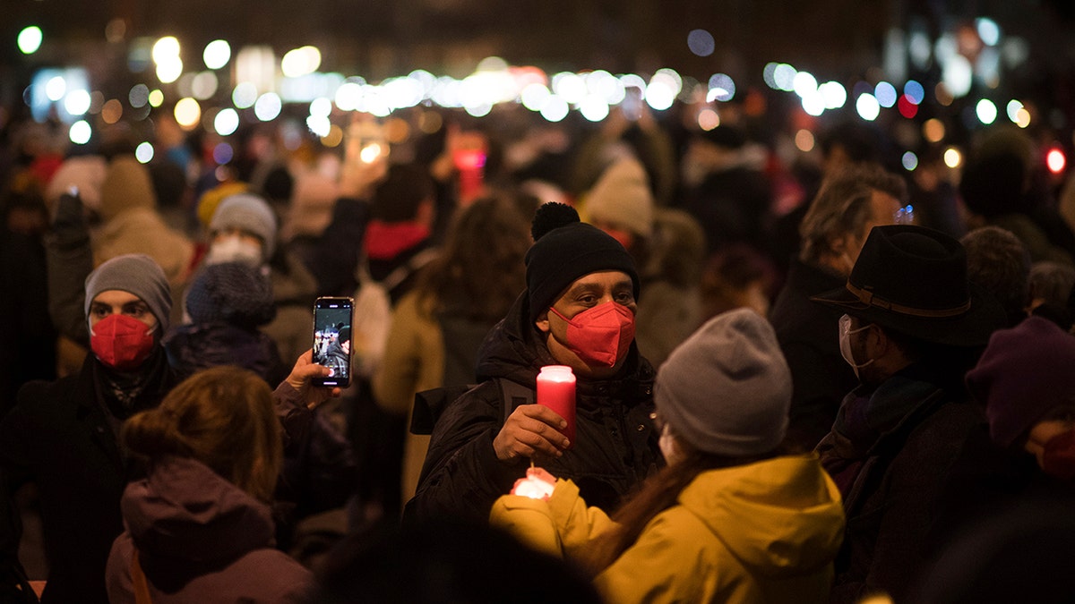 People hold candles, in memory of those who have died  in Austria of coronavirus, in Vienna, Sunday, Dec. 19, 2021.