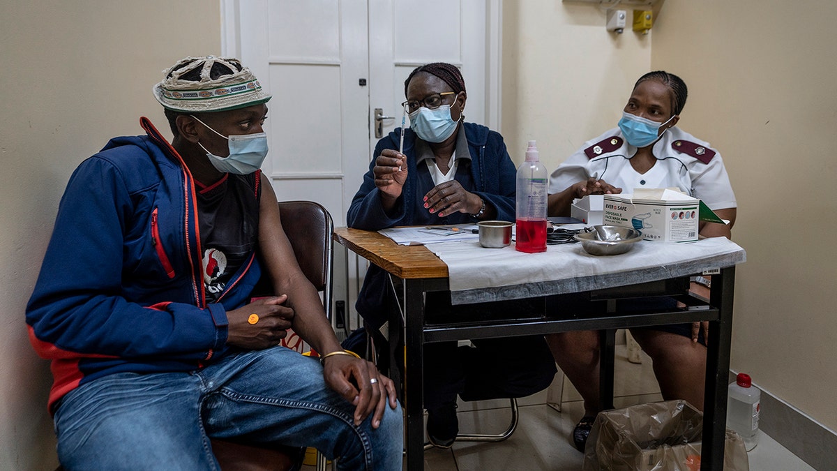Medical staff talk to a man about to be vaccinated against COVID-19 at the Hillbrow Clinic in Johannesburg, South Africa, Monday Dec. 6, 2021. 
