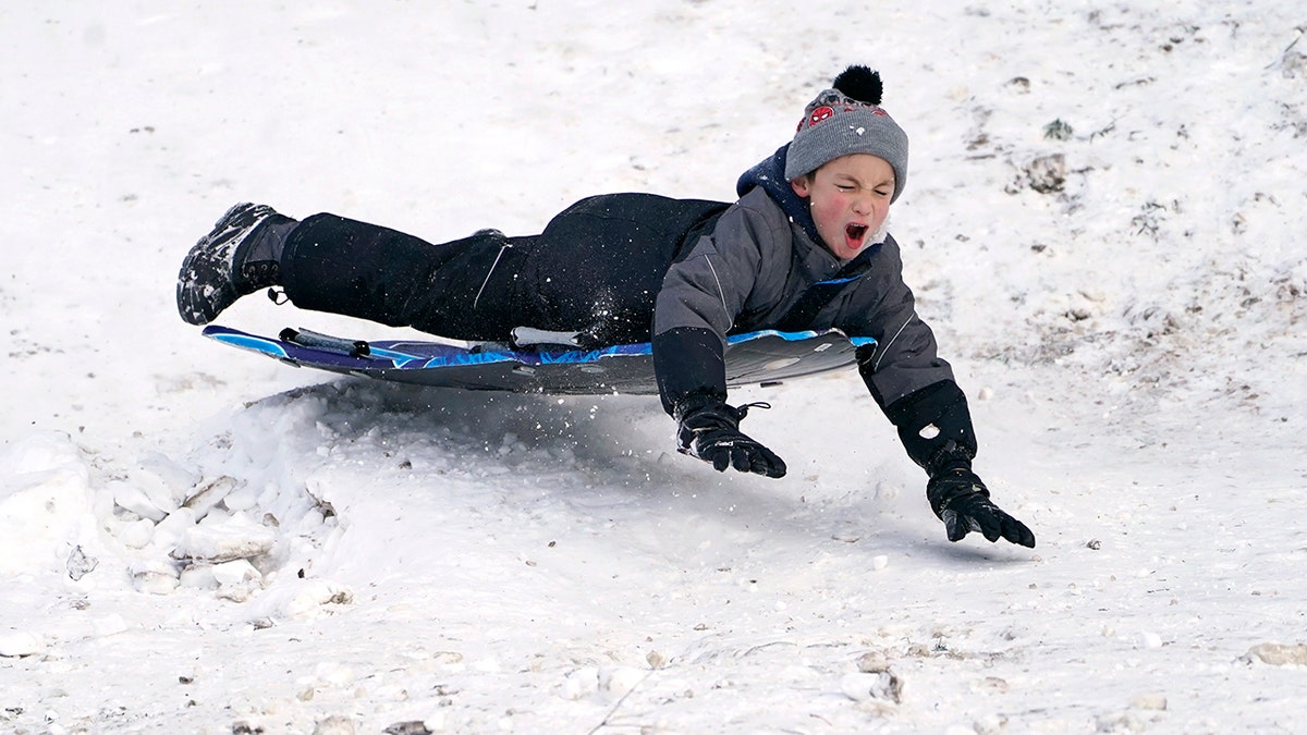 Titus Gonzalez goes airborne after hitting a bump while sledding where nearly a foot of snow fell over the weekend, Monday, Dec. 27, 2021, in a city park in Bellingham, Washington. 