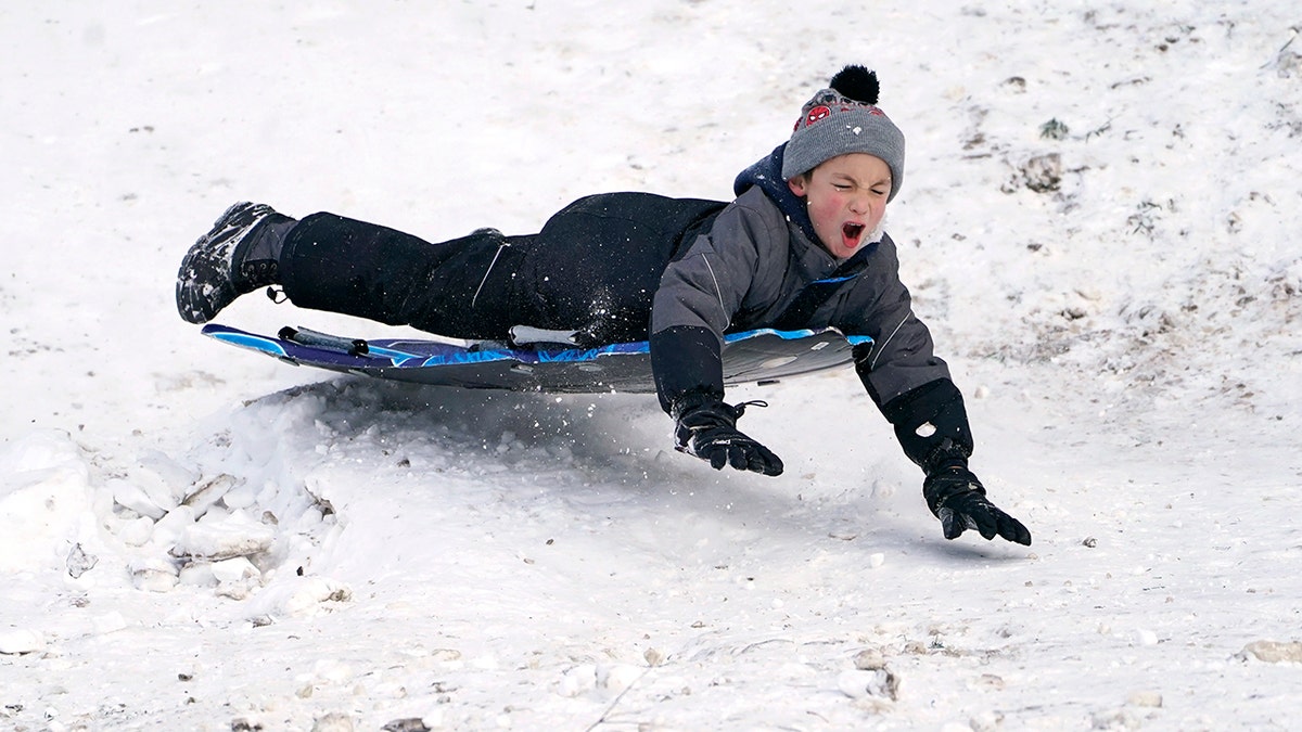 Titus Gonzalez goes airborne after hitting a bump while sledding where nearly a foot of snow fell over the weekend, Monday, Dec. 27, 2021, in a city park in Bellingham, Washington.