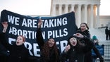 WASHINGTON, DC - DECEMBER 01: (L-R) Lila Bonow, Alana Edmondson and Aiyana Knauer prepare to take abortion pill while demonstrating in front of the U.S. Supreme Court as the justices hear hear arguments in Dobbs v. Jackson Women's Health, a case about a Mississippi law that bans most abortions after 15 weeks,  on December 01, 2021 in Washington, DC. With the addition of conservative justices to the court by former President Donald Trump, experts believe this could be the most important abortion case in decades and could undermine or overturn Roe v. Wade. (Photo by Chip Somodevilla/Getty Images)