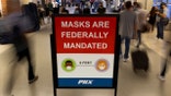 FILE PHOTO: Air travelers make their way past a sign mandating face masks for all during the outbreak of the coronavirus disease (COVID-19) at Phoenix international airport in Phoenix, Arizona, U.S. September 24, 2021. REUTERS/Mike Blake
