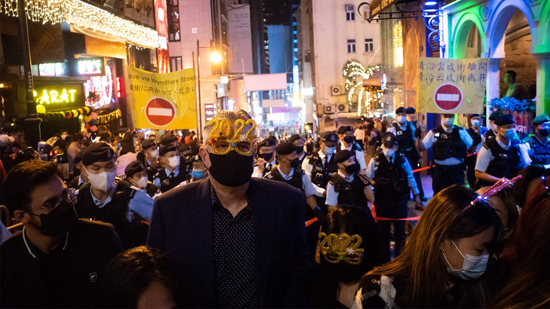 A man wearing festive glasses stands in front of police at Hong Kongs Lan Kwai Fong area on January 1, 2022.