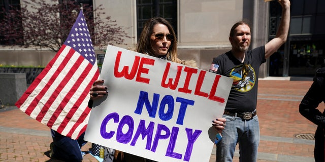A protestor carries a sign reading "We Will Not Comply" during a demonstration outside the Virginia State Capitol to protest Virginia's stay-at-home order 