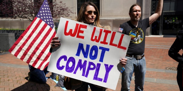 A protestor carries a sign reading "We Will Not Comply" during a demonstration outside the Virginia State Capitol to protest Virginia's stay-at-home order 