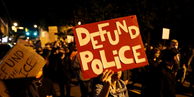Demonstrators hold a sign reading "Defund Police" during a protest over the death of a Black man, Daniel Prude, after police put a spit hood over his head during an arrest on March 23, in Rochester, New York, Sept. 6, 2020.