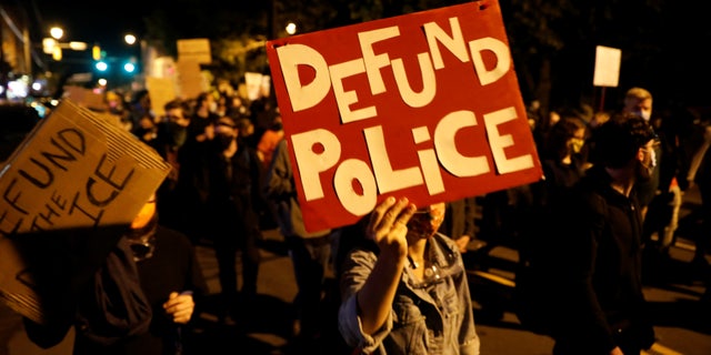 Demonstrators hold a sign saying "defund the police" during a protest over the death of a Black man, Daniel Prude, after police put a spit hood over his head during an arrest in Rochester, N.Y., Sept. 6, 2020.