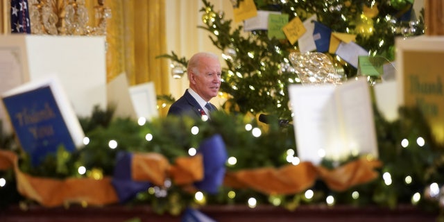 Reflected in a mirror decorated for Christmas, President Joe Biden delivers remarks to commemorate World AIDS Day at the White House on Dec. 1, 2021. (REUTERS/Kevin Lamarque)