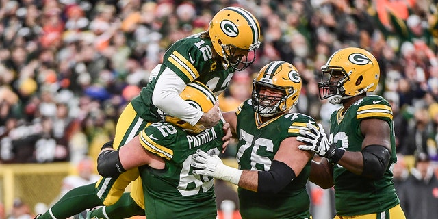 Green Bay Packers quarterback Aaron Rodgers (12) is lifted up by guard Lucas Patrick (62) after setting the franchise record for most passing TDs in the first quarter during the game against the Cleveland Browns at Lambeau Field. 
