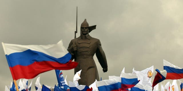 Pro-Kremlin activist hold Russian flags near a monument to Red Army soldier as they rally in the southern Russian city of Stavropol, on March 18, 2014, to celebrate the incorporation of Crimea. 