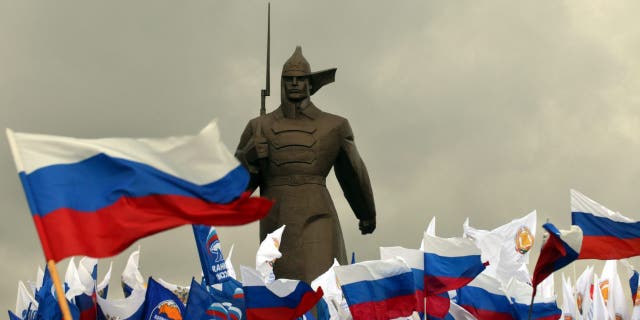 Un militant pro-Kremlin tient des drapeaux russes près d'un monument dédié à un soldat de l'Armée rouge alors qu'ils se rassemblent dans la ville de Stavropol, dans le sud de la Russie, le 18 mars 2014, pour célébrer l'incorporation de la Crimée.