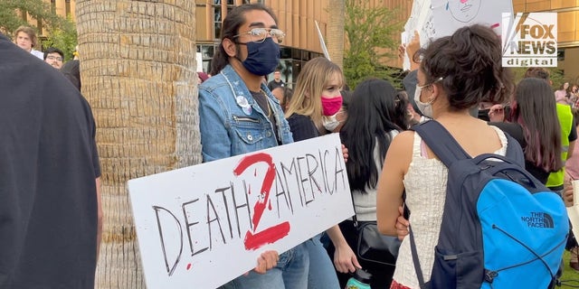 A protester holds a "Death to America" sign at a rally protesting Kyle Rittenhouse at Arizona State University.