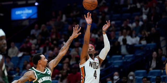 New Orleans Pelicans guard Devonte' Graham (4) shoots over Milwaukee Bucks guard George Hill (3) in the first half of an NBA basketball game in New Orleans, 金曜日, 12月. 17, 2021.
