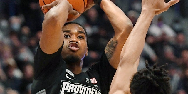 Providence's A.J. Reeves (11) makes a 3-point basket as Connecticut's Andre Jackson defends in the first half of an NCAA college basketball game, Sabato, Dic. 18, 2021, in Hartford, Conn.