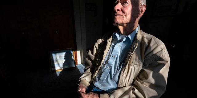 Pearl Harbor survivor and World War II Navy veteran David Russell, 101, poses for a photo along with a painting of the USS Oklahoma at his home on Monday, Nov. 22, 2021, in Albany, Ore. (AP Photo/Nathan Howard)