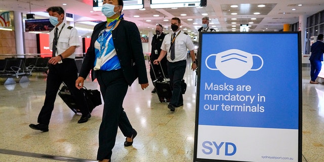 FILE - A flight crew walk through the terminal at Sydney Airport on Nov. 29, 2021. 