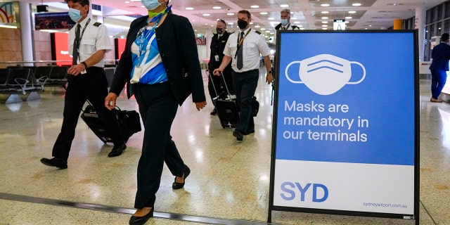 FILE - A flight crew walk through the terminal at Sydney Airport on Nov. 29, 2021.