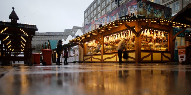 DOSSIER - Des clients attendent devant un marché de Noël un matin pluvieux dans le centre de Berlin, en Allemagne, le mardi 30 novembre 2021. (AP Photo/Markus Schreiber, File)