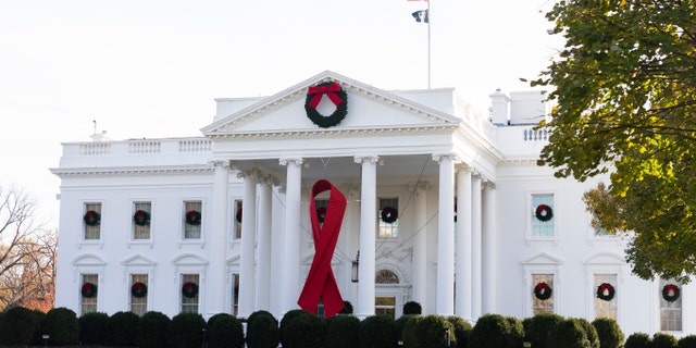 The North Portico of the White House is adorned with a huge red ribbon to commemorate the annual World AIDS Day, Wednesday, Dec. 1, 2021, in Washington. The Biden administration in its new HIV/AIDS strategy is calling racism "a public health threat" that must be fully recognized as the world looks to end the epidemic. (AP Photo/Manuel Balce Ceneta)