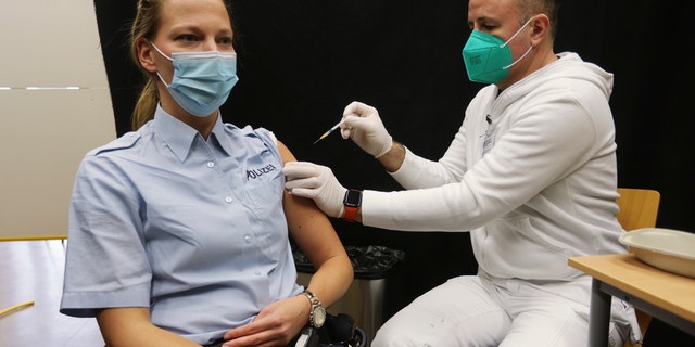 A policewoman gets a booster vaccination against the coronavirus and the COVID-19 disease in Hilden, Germany, Thursday, Dec. 2, 2021. (David Young/dpa via AP)
