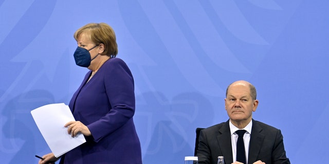 La chancelière allemande Angela Merkel, à gauche, et le ministre des Finances Olaf Scholz arrivent pour une conférence de presse à la suite d'une réunion avec les chefs de gouvernement des États fédéraux allemands à la Chancellerie de Berlin, le jeudi 2 décembre 2021. (John Macdougall/Pool Photo via PA)