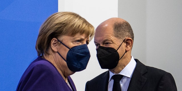 German Chancellor Angela Merkel, left, and Finance Minister Olaf Scholz arrive for a press conference following a meeting with the heads of government of Germany's federal states at the Chancellery in Berlin, Thursday, Dec. 2, 2021.  (John Macdougall/Pool Photo via AP)