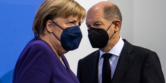 German Chancellor Angela Merkel, left, and Finance Minister Olaf Scholz arrive for a press conference following a meeting with the heads of government of Germany's federal states at the Chancellery in Berlin, Thursday, Dec. 2, 2021. (John Macdougall/Pool Photo via AP)