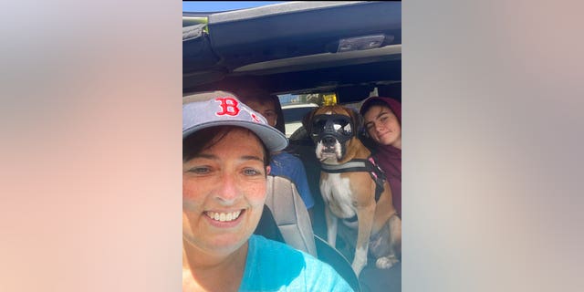 This 2021 photo provided by Cheri Burness shows Burness and her family, including dog Lilikoi, in car in Honolulu. Hundreds of military families living near Pearl Harbor have complained of stomach pain, nausea and other health ailments amid concerns the Navy's water system may have been contaminated by a fuel leak.(Cheri Burness via AP)