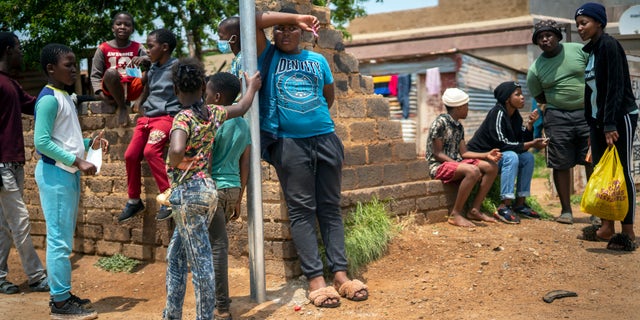 Residents stand in the streets of Lawley, South Africa, during a visit of local government officials for the launch of the Vooma vaccination program against COVID-19 Friday Dec. 3, 2021. South Africa has accelerated its vaccination campaign a week after the discovery of the omicron variant of the coronavirus. (AP Photo/Jerome Delay)