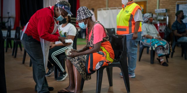 An Orange Farm, South Africa, resident listens to a nurse after receiving his jab against COVID-19 Friday Dec. 3, 2021 at the Orange Farm multipurpose center. South Africa has accelerated its vaccination campaign a week after the discovery of the omicron variant of the coronavirus. (AP Photo/Jerome Delay)