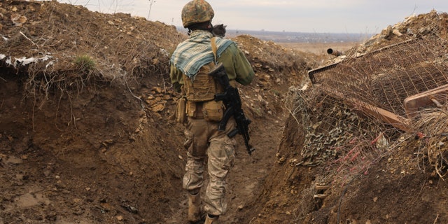 A Ukrainian soldier holds a cat and walks in a trench on the line of separation from pro-Russian rebels near Debaltsevo, Donetsk region, Ukraine, Ukraine Friday, Dec 3, 2021. In this Friday, the Ukrainian defense minister warned that Russia could invade his country next month. Russia-West tensions escalated recently with Ukraine and its Western backers becoming increasingly concerned that a Russian troop buildup near the Ukrainian border could signal Moscow's intention to invade. (AP Photo/Andriy Dubchak)