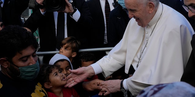 Pope Francis meets migrants during his visit at the Karatepe refugee camp, on the northeastern Aegean island of Lesbos, Greece, Sunday, Dec. 5, 2021. Pope Francis is offering comfort migrants at a refugee camp on the Greek island of Lesbos. He is blasting what he says is the indifference and self-interest shown by Europe "that condemns to death those on the fringes." (AP Photo/Alessandra Tarantino)