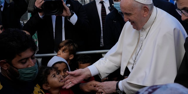 Pope Francis meets migrants during his visit at the Karatepe refugee camp, on the northeastern Aegean island of Lesbos, Greece, Sunday, Dec. 5, 2021. Pope Francis is offering comfort migrants at a refugee camp on the Greek island of Lesbos. He is blasting what he says is the indifference and self-interest shown by Europe "that condemns to death those on the fringes." (AP Photo/Alessandra Tarantino)