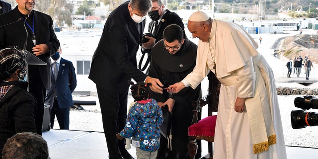 Pope Francis meets a child during a ceremony at the Karatepe refugee camp, on the northeastern Aegean island of Lesbos, Greece, Sunday, Dec. 5, 2021. 