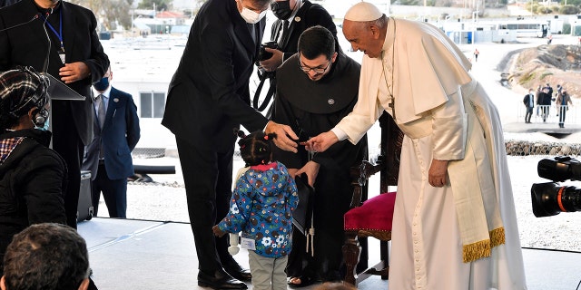 Pope Francis meets a child during a ceremony at the Karatepe refugee camp, on the northeastern Aegean island of Lesbos, Greece, Sunday, Dec. 5, 2021.