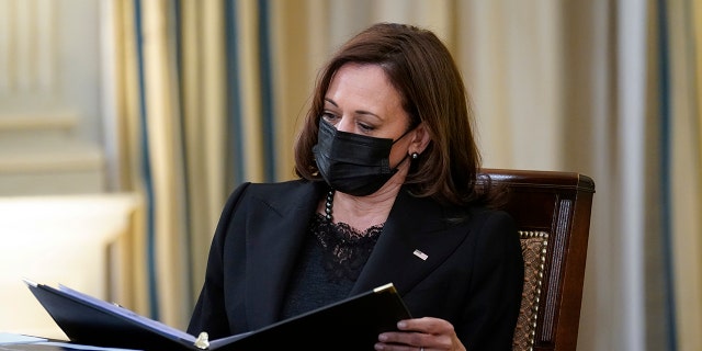 Vice President Kamala Harris looks over documents during a meeting with President Joe Biden and members of the White House COVID-19 Response Team in the State Dining Room of the White House in Washington, Thursday, Dec. 9, 2021.