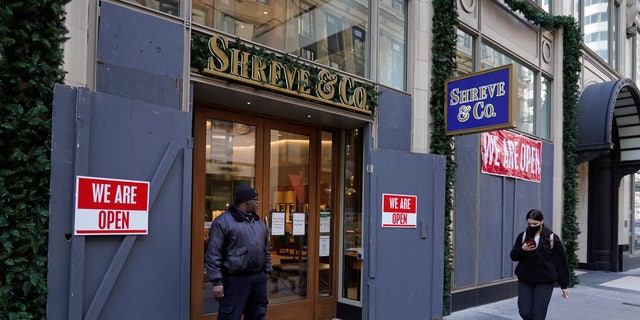 A security guard stands outside the heavily boarded Shreve &amp; Co. jewelry store in San Francisco, Thursday, Dec. 2, 2021. (AP Photo/Eric Risberg)