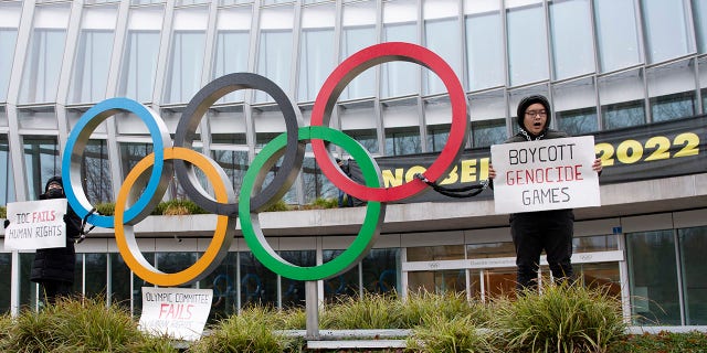 Protesters hold protest posters during a protest against Beijing 2022 Winter Olympics by activists of the Tibetan Youth Association in Europe front of the International Olympic Committee (IOC) headquarters in Lausanne, Switzerland, Saturday, Dec. 11, 2021.