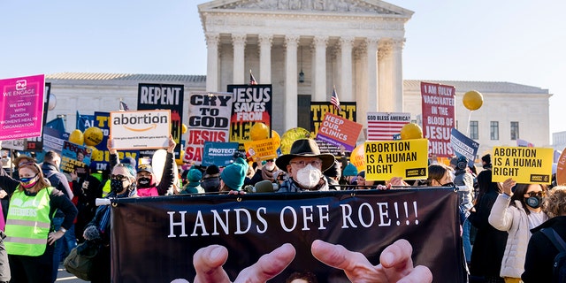 Stephen Parlato of Boulder, Colorado, holds a sign that reads "Hands Off Roe!!!" as abortion rights advocates and anti-abortion protesters demonstrate in front of the U.S. Supreme Court, Dec. 1, 2021, in Washington. 