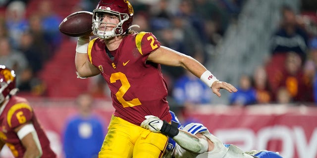 FILE - Southern California quarterback Jaxson Dart (2) throws a pass while being tackled by BYU linebacker Ben Bywater (33) during the second half of an NCAA college football game in Los Angeles, Saturday, Nov. 27, 2021.