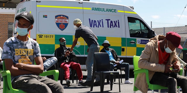 People wait to be vaccinated by a member of the Western Cape Metro EMS at a mobile "Vaxi Taxi," an ambulance converted into a mobile COVID-19 vaccination site in Blackheath in Cape Town, South Africa, Tuesday, Dec. 14, 2021. 