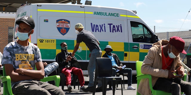 People wait to be vaccinated by a member of the Western Cape Metro EMS at a mobile "Vaxi Taxi," an ambulance converted into a mobile COVID-19 vaccination site in Blackheath in Cape Town, South Africa, Tuesday, Dec. 14, 2021. 