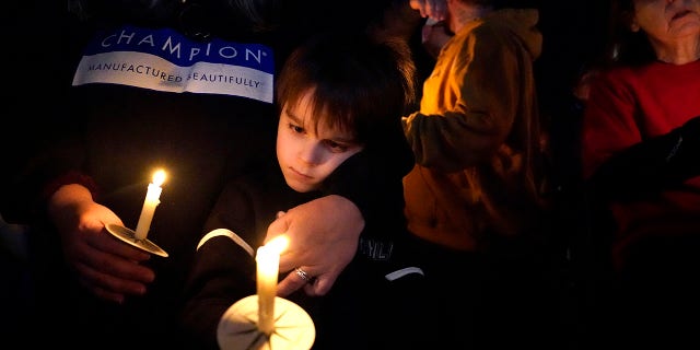 Tard mardi 14 décembre 2021, Mayfield, Ky.  À l'intérieur, un garçon tient une bougie après un ouragan qui a ravagé la région il y a plusieurs jours. 