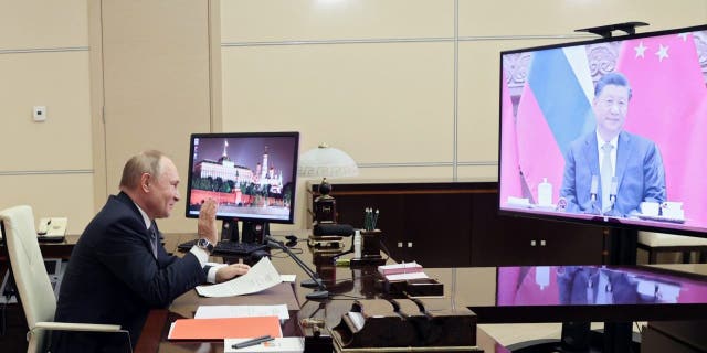 Russian President Vladimir Putin gestures during his conference with Chinese President Xi Jinping, right on the screen, in Moscow, Russia, Wednesday, Dec. 15, 2021.