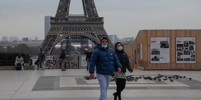 People wearing face masks to protect against COVID-19 cross the Trocadero Plaza in Paris, 수요일, 12 월. 15, 2021. (AP Photo/Michel Euler)